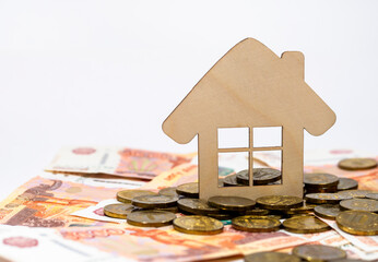 A small house standing on money and coins. Real estate concept.