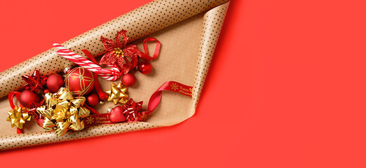 Wall Mural - Christmas decorations, glass balls, ribbons, bows, candy canes, roll of wrapping paper on red background. New Year, Christmas holidays. festive winter season concept. top view. banner. copy space