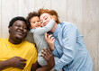 © lordn - Portrait of a beautiful cheerful smiling mixed-race family. Lying on a floor hugging and having fun. Togetherness, family, and love concept.