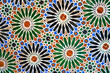 Geometric seamless andalusian moroccan islamic arabic round star floral pattern in green orange made out of ceramic tiles in Spain Sevilla