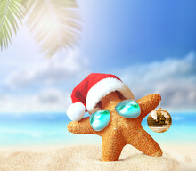 Starfish In Santa Claus Hat And Christmas Ball On A Summer Beach. Merry Christmas
