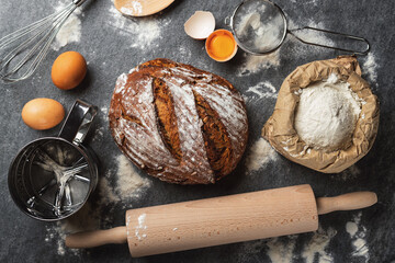 Poster - Whole loaf of fresh homemade bread with ingredients for cooking on the table in the bakery top view