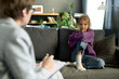 © Mediaphotos - Little girl sitting on sofa in living room and having conversation with psychologist