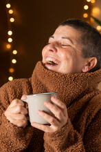 Woman With Winter Jumper And Coffee Cup, Out-of-focus City Or Celebration Lights Behind.