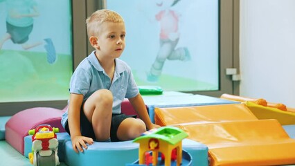 Wall Mural - cute little boy sitting in the playroom and playing, full shot kindergarten. High quality 4k footage