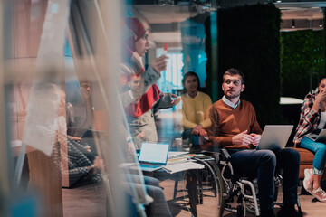 An older Muslim businesswoman presents a project to a young diverse team of people in a modern office