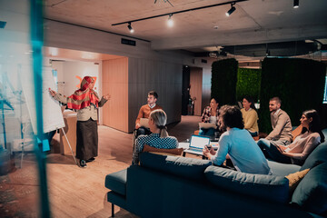 Wall Mural - An older Muslim businesswoman presents a project to a young diverse team of people in a modern office