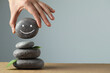 Woman putting stone drawn happy face onto stack against grey background, closeup and space for text. Zen concept