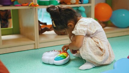 Wall Mural - cute dark-haired girl playing with a toy in the playroom, toys on the shelves in the background full shot. High quality 4k footage