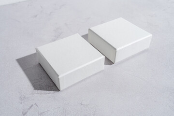 Two white square gift boxes mockup on gray concrete background. From above, top view, minimalist concept