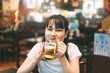 © dodotone - Portrait of young adult asian woman drinking beer in izakaya japanese restaurant
