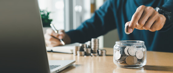 Wall Mural - Hand putting coins in a piggy bank for save money and Saving Money concept.