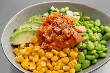 Poster - Closeup of poke bowl with salmon, avocado, edamame beans, cucumber, corn and sesame seeds.