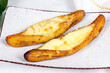 Baked Ripe Plantains with Cheese (Plantain Canoe or Platanos Asados Con Queso) on a plate on wooden background.