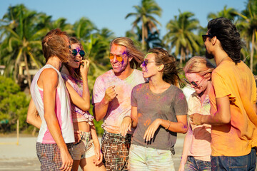 mixed race friends having fun with colors on seaside outdoors in Goa India