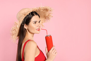 Wall Mural - Beautiful young woman with straw hat drinking from tin can on pink background. Space for text