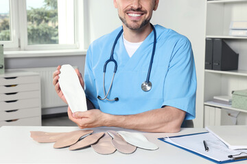 Sticker - Male orthopedist showing insoles in hospital, closeup