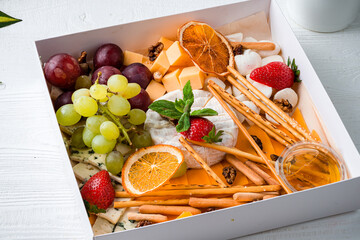 Wall Mural - cheese plate a box with a set of cheeses for food delivery with cheese, bread sticks