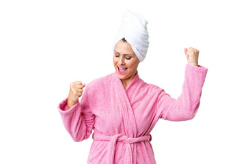 Wall Mural - Middle age caucasian woman in a bathrobe over isolated background celebrating a victory