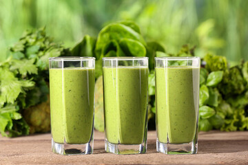 Glasses of fresh green smoothie and ingredients on wooden table