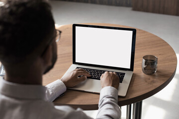 Young man using laptop computer with blank empty mockup screen. Business man working at office. Freelance, student lifestyle, e-learning, shopping online, web site, technology concept