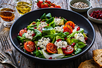 Fresh vegetable salad with feta cheese and pomegranate  on wooden table
