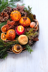 Sticker - Christmas holiday. Winter altar for Yule sabbat. Moon amulet, candle, cinnamon, nuts, cones, decorated oranges and dry orange slices, fir branches in plate on wooden table. Festive winter season