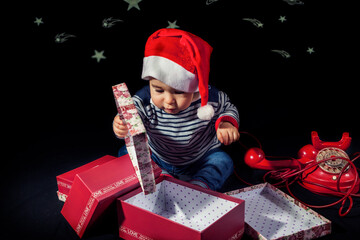 cute little boy opening christmas presents near red vintage telephone sitting