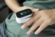 Woman resting at home using pulse oximeter to monitor blood oxygen levels and pulse rate. finger inserted into the pressure oximeter to assess health from the living room home.