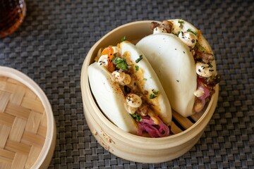 Poster - Closeup of delicious Gua bao or pork belly buns, traditionally served in bamboo basket, on table mat