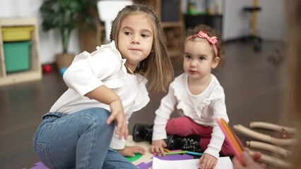 Wall Mural - Two little girls drawing on notebook sitting on floor at kindergarten