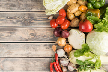 Colorful food composition of assortment of organic garden vegetables on wooden background. Grocery, food store. Balanced food styling and flyer. Vitamin salad recipe. Copy space, top view, flat lay