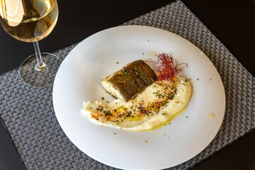 Poster - Grilled fish fillet with mashed potatoes and spices served on white plate with white wine