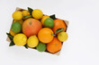 Mix of citrus fruits. Oranges, grapefruit, lemons and limes with leaves in wooden box on white background. Top view. Photo from above.