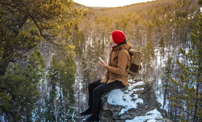 a man tourist with a phone in his hand on top far from civilization . activity and availability of m