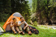 © Drobot Dean - White young couple drinking tea resting by tent in green forest