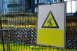 Yellow electric safety sign outside on metal gate