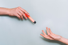 Passing An Electronic Cigarette From One Hand To Another Against Light Background.
