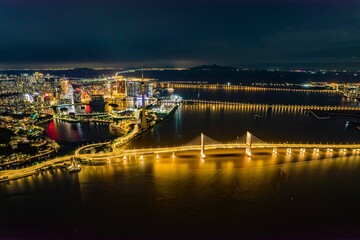 Sticker - Aerial long exposure view of a futuristic illuminated city on an island with a bridge at night