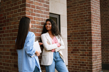 Young indian women smiling and talking while standing by building