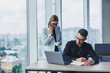 © Дмитрий Ткачук - A businessman is working on a laptop while talking while his colleague is listening. Work in a modern bright office