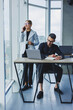 © Дмитрий Ткачук - A businessman is working on a laptop while talking while his colleague is listening. Work in a modern bright office