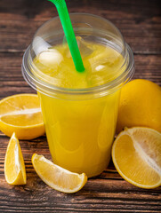 Wall Mural - Lemonade in a take away glass with cut lemon next to it on wooden table