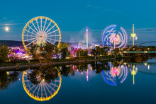 Germany, Baden-Wurttemberg, Stuttgart, Amusement Park Rides Glowing In Riverside Festival Area At Night
