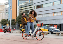 Happy Boyfriend Enjoying With Girlfriend Riding Bicycle At Footpath