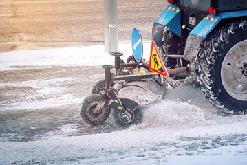 Wall Mural - Tractor sweep snow with rotating brush from pedestrian zone, sidewalk snow management during blizzard. Snow plow service remove snow and ice from road, winter road maintenance.