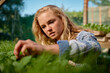 © StratfordProductions - Young caucasian woman looking down while examining plants in plant nursery