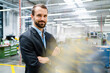 © Westend61 - Smiling businessman standing with arms crossed at factory