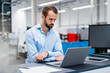 © Westend61 - Focused businessman watching laptop at factory