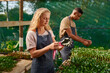 © StratfordProductions - Young multiracial couple wearing aprons while gardening in plant nursery